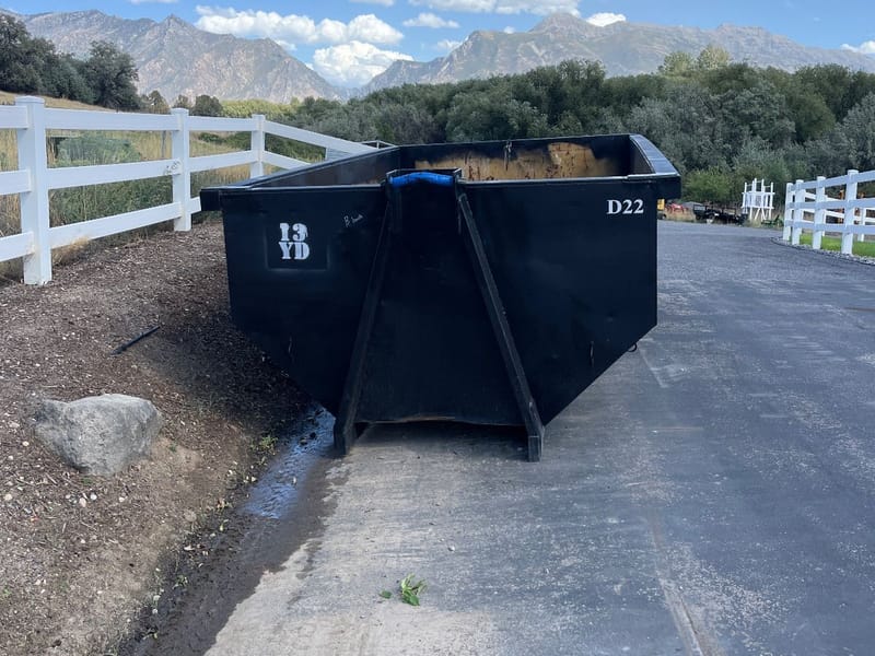 Black 13 yard Dirty Devil roll-off dumpster on a job site